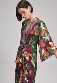 Lebendiger, floral bedruckter Kimono in reichhaltigem Bordeauxrot und Grün. Mit tiefem V-Ausschnitt, weiten Ärmeln und einem drapierten Vorderteil mit Knotendetail.