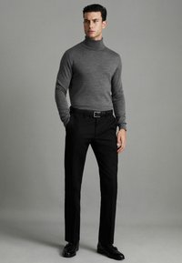 Pulover gri cu guler înalt, pantaloni de costum negri, ajustați, și pantofi negri. Textură netedă, design minimal și culori neutre.