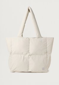 Gevoerde tas in licht beige met twee korte handvatten, met een gewatteerd oppervlak en een klein merklogo in de onderste hoek.