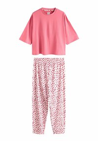 Růžový top s krátkými rukávy a kulatým výstřihem, doplněný bílými kalhotami s rozptýleným vzorem červených srdcí. Měkký bavlněný materiál.