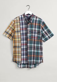 Camisa de cuadros de manga corta que presenta una mezcla de colores: amarillo, marino, verde y rojo, con un cuello abotonado y un bolsillo en el pecho. Material de mezcla de algodón.