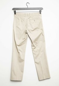 Beige housut suoralla lahjeompelella, valmistettu sileästä kankaasta. Varustettu takataskulla, jossa on nappisulku. Ripustettuna mustalle ripustimelle.