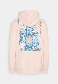 Sudadera con capucha de color rosa claro que presenta un diseño gráfico de una mano con elementos del sol y la luna, acentos en azul y detalles de impresión texturizada.