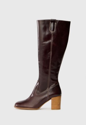 Knee-high ruskeat nahkasaappaat, joissa on kiiltävä pinta, erottuvaa ommelta ja tukevat paksut puukorkot.