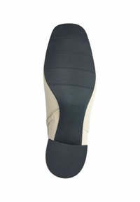 Suela de calzado beige con una base de goma negra texturizada, forma moldeada y tamaño estampado "37". Presenta ranuras para mayor tracción.