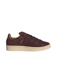 Brown suede sneaker with beige sole, featuring three side stripes, rounded toe, and flat laces. Branding visible on the outer side.