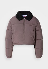 Veste matelassée courte mauve avec col en fausse fourrure noire, fermeture éclair frontale, poches latérales et logo Tommy Jeans sur la poitrine.