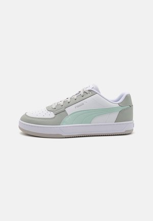 Baskets basses Puma blanches et gris clair avec bande vert menthe, fermeture à lacets et semelle en caoutchouc, vues de côté.