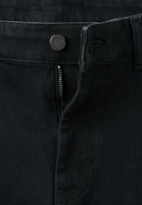 Nahaufnahme von schwarzen Jeans aus Denim mit einem teilweise geöffneten Reißverschluss und einem Metallknopf, der mit "KING DENIM" graviert ist.