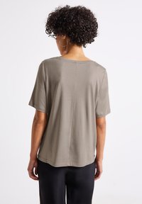 Ljus olivgrön t-shirt med korta ärmar, rund halsringning och avslappnad passform. Slät textur med detalj av mitt bakseam.