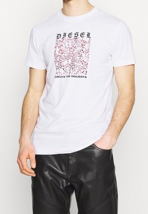 T-shirt en coton blanc avec un motif graphique comportant des motifs rouges et le texte noir en gras "DIESEL" et "SURVIVE THE HOLIDAYS". Manches courtes.