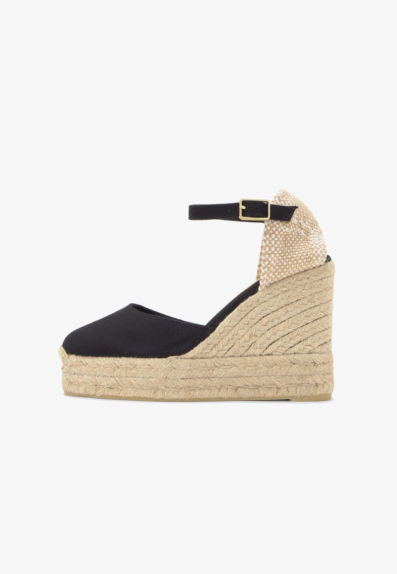 Espadrille compensée avec tige en tissu noir, contrefort en tissage beige, semelle plateforme en jute et bride de cheville noire avec boucle dorée.