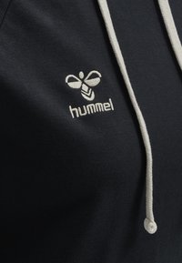 Felpa con cappuccio di un blu navy scuro, con un cordino beige chiaro e logo ricamato. Tessuto morbido e dalla texture liscia.