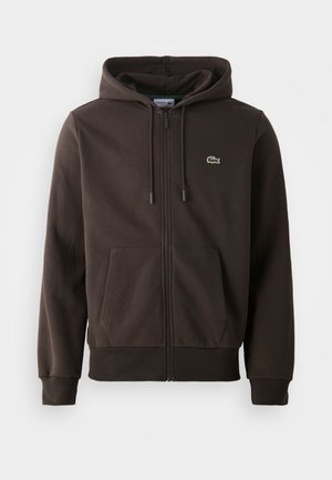 Sudadera con capucha marrón oscuro con cremallera, bolsillos delanteros, capucha con cordón y pequeño logo verde de cocodrilo en el pecho izquierdo.