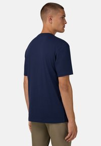 Námořnická modrá tričko s krátkým rukávem z bavlny; klasický výstřih, volný střih, hladká textura, minimalistický design, bez viditelných log nebo vzorů.