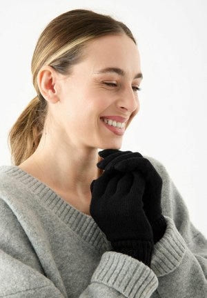 Black knit gloves with ribbed cuffs, made from soft material. The design features contouring for fingers and a textured finish.
