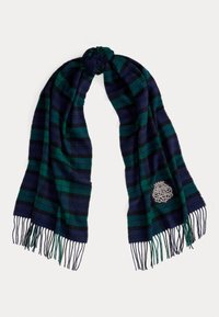 Ruuduline sall, millel on vahelduvad tumesinised ja rohelised triibud, hõbedane dekoratiivne embleem ning allosas frieside ääred.