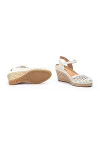 Sandalias de cuña blancas con detalles recortados, plantilla de yute trenzado, correa para el tobillo y suela de goma. Textura suave y diseño de punta abierta.
