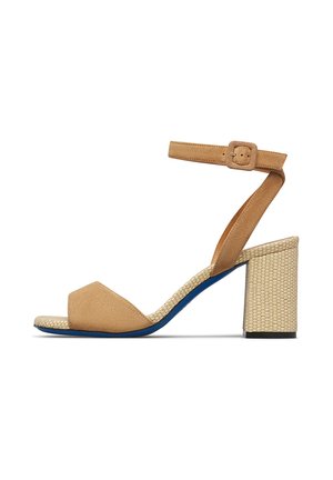 Hellbraune Wildleder-Sandalette mit offener Zehenpartie, geflochtenem Blockabsatz und verstellbarem Knöchelriemen vor weißem Hintergrund.