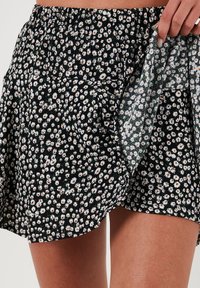 Schwarzer Blumenkleid mit weißem Gänseblümchenmuster, elastischem Taillenbund und weichem Stoffgefühl. Hat ein fließendes Design mit geschichteten Stoffdetails.