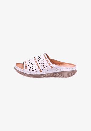 White slip-on sandal with cut-out floral patterns, brown cushioned insole, and a thick textured beige sole.