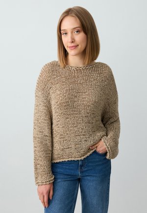Beige gestrickter Pullover mit lockerer Passform, weitem Ausschnitt und strukturiertem Muster. Kombiniert mit blauen Jeans, die einen lässigen, entspannten Stil zeigen.