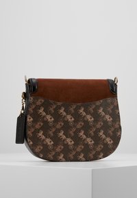 Borsa a tracolla marrone e nera con patta in suede, design a motivo cavallo e carro, rifiniture in pelle nera e etichetta nera attaccata con catena.
