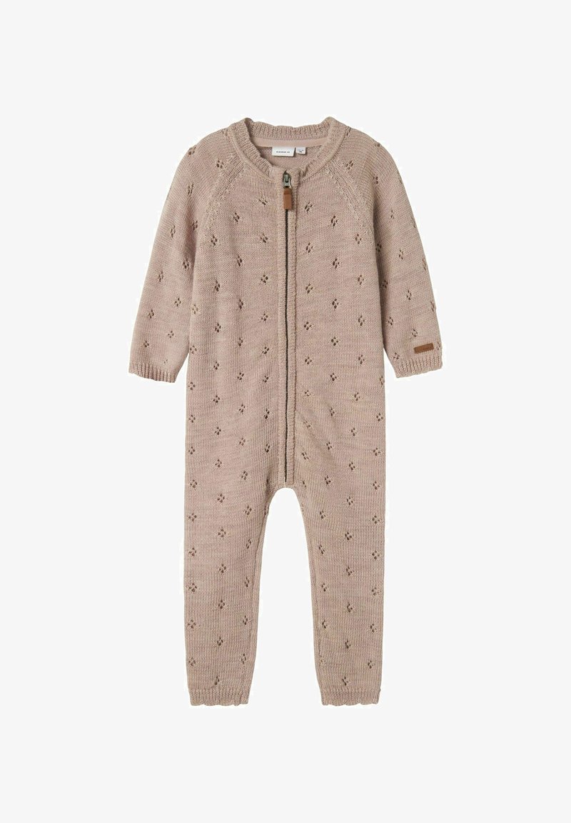 Knitted beige onesie with a full front zipper, featuring a diamond pattern, ribbed cuffs, and a leather tag on the sleeve.