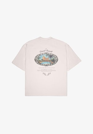 Lyserosa bomull t-skjorte med et grafisk motiv av et feriested med palmer, omgitt av dekorative svarte blomsterdetaljer og tekst.
