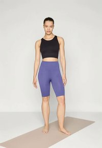 Black crop top and purple high-waisted bike shorts, made of textured fabric, fitted design, with a smooth finish and no visible logos.