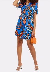 Bla dresses aus Stoff mit lebhaften orange und aqua wirbelnden Mustern, kurzen Ärmeln, durchgehender Knopfleiste und einer gebundenen Taillendetail. Inklusive einer orangefarbenen Tasche.
