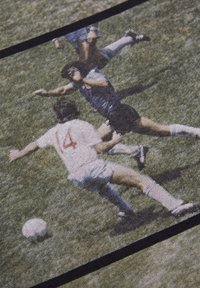 Retro sportsgrafik med to spillere, en iført hvid med det røde nummer 14, og en anden i blå, begge på græs med en fodbold.