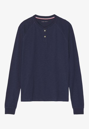 Chemise à manches longues bleu marine avec un col rond, une patte de boutonnage à deux boutons et des poignets côtelés. Tissu doux et texturé avec des manches raglan.