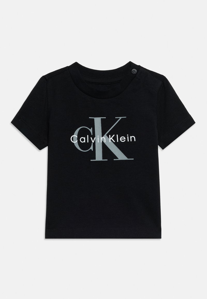 T-shirt noir à manches courtes pour bébé avec un grand logo "cK" gris et "Calvin Klein" blanc sur le devant, col rond avec bouton à l'épaule.