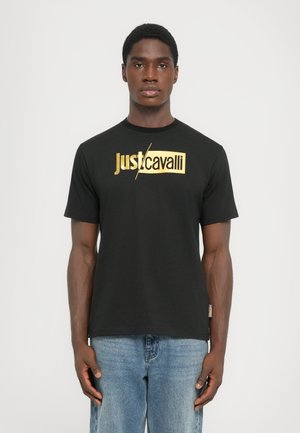 Camiseta de algodón negra con un logo en foil dorado de "Just Cavalli" en el pecho. Mangas cortas y un cuello redondo clásico.