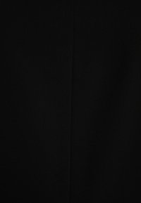 Svart tyg med en slät textur och subtilt diagonalt vävmönster. Ytan är odekorerad med en central vertikal söm.