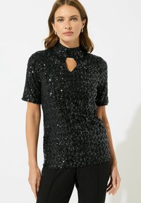 Schwarz glitzerndes Oberteil mit kurzen Ärmeln, das über einen Schlüssellochausschnitt und eine vertikale Rippstruktur verfügt. Figurbetonte Silhouette, glattes und schimmerndes Material.