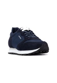 Marineblauwe sneaker met een mix van suede en gladde stof, witte veters en een getextureerde rubberen zool met een verhoogd patroon.