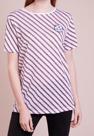 White short-sleeve t-shirt featuring diagonal red stripes and a small cartoon face patch on the chest. Soft fabric with a relaxed fit.
