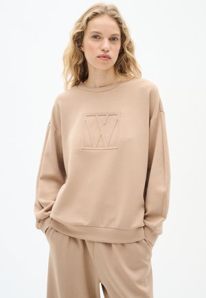 Beige mikina s vroubkovaným kulatým výstřihem a dlouhými rukávy, se vzorovaným logem uprostřed. Vyrobena z měkké, strukturované tkaniny.