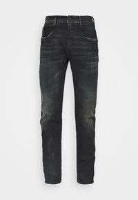 Jeans de mezclilla negra con ajuste slim, que presentan un acabado desgastado, diseño de cinco bolsillos y una etiqueta negra en el bolsillo trasero derecho.