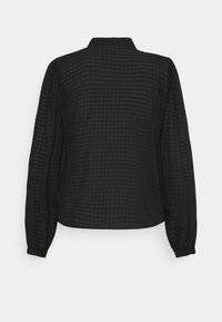 Blouse noire avec un motif de grille texturé, manches longues et col. Le tissu est léger et semi-transparent, avec une coupe décontractée.