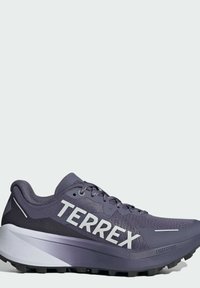 Zapatilla deportiva morada con parte superior de malla, con la marca "TERREX" en blanco y suela texturizada. Presenta una entresuela blanca acolchada y acentos reflectantes.