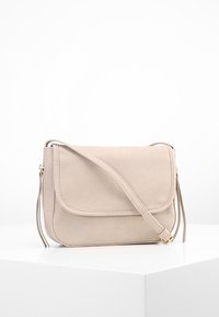 Beżowa skórzana torebka na ramię z klapką, regulowanym paskiem i gładką fakturą, ozdobiona złotymi elementami metalowymi.