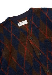 Cardigan a quadri marrone e blu realizzato in tessuto testurizzato, con scollo a V, bottoni scuri e un'etichetta che riporta "Universal Works."