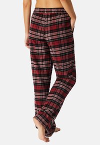 Pantaloni da pigiama a quadri rossi e neri con vita elasticizzata e tasche laterali, caratterizzati da una superficie morbida e una vestibilità rilassata.