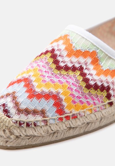 Espadrille à enfiler avec motif en zigzag multicolore en tricot et semelle en jute tissé sur un fond clair.