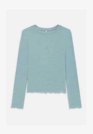 Camisa de manga longa canelada azul clara com bordas em forma de onda nos punhos e na barra, decote redondo, disposta sobre um fundo branco.