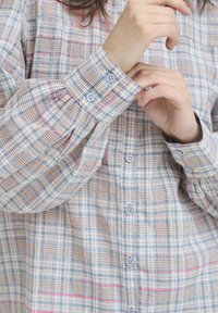 Licht geruit overhemd met knopen in tinten blauw, bruin en roze. Lange mouwen met manchetten met knopen en een ruime pasvorm. Getextureerde stof.