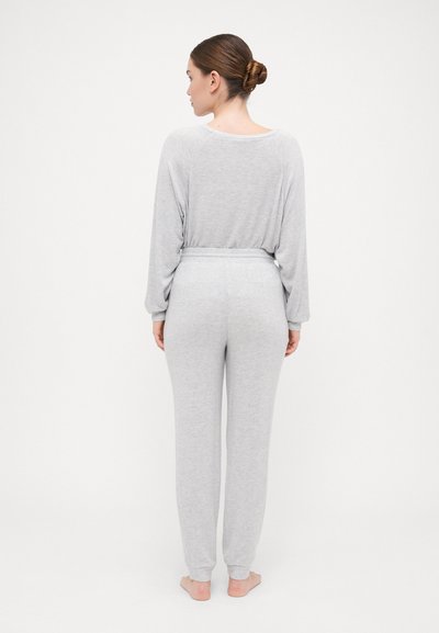 Ensemble de loungewear gris comprenant un haut à manches longues et un pantalon à taille élastique. Texture douce avec des poignets ajustés, finition lisse et coupe ample.